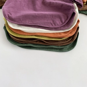 Close-up of slub cotton T-shirt curved hems in various colors showing fabric texture