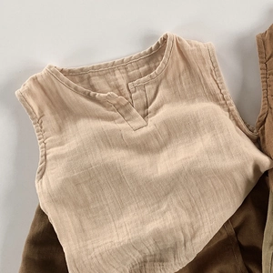 Dettaglio del top beige senza maniche per bambini che mostra la trama del cotone e lino