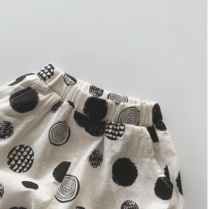 Gros plan du pantalon enfant en coton avec taille élastique et motifs à pois noirs