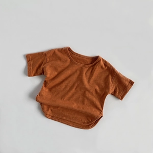 Detail of bamboo cotton fabric texture and curved hem on a rust red kids t-shirt