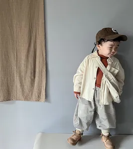 Full view of boy's Korean style beige cargo shirt with striped wide-leg trousers outfit