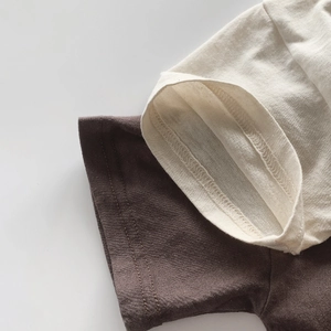 Detailaufnahme der doppelt genähten Baumwoll-T-Shirt-Ärmel in Beige und Dunkelbraun