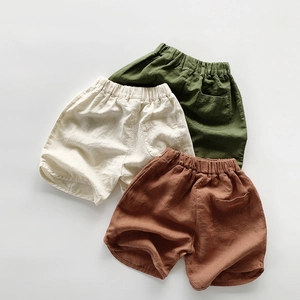 Flat lay of cotton linen kids shorts in army green, beige, and caramel summer colors