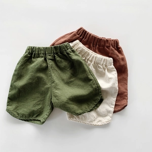 Detail of cotton linen kids shorts showing forest green, cream white and brick red colors