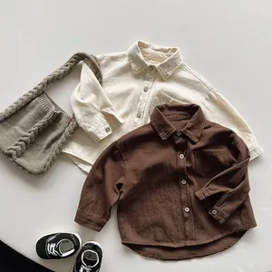 Close-up of cotton long sleeve kids' shirts in cream and brown with textured fabric