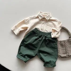 Flat lay of cotton linen shirt and trousers set for kids with woven bag accessory