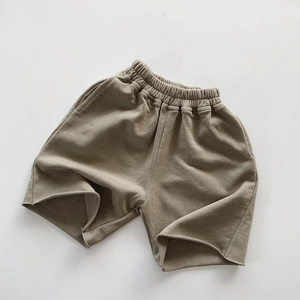 Detail of olive green kids cotton shorts with elastic waistband and raw-cut hem finish