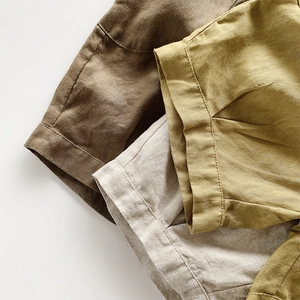 Détail de l'ourlet roulé et de la texture du lin naturel en brun, beige et jaune moutarde