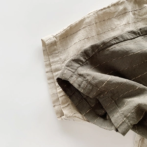 Dettaglio del tessuto in cotone e lino a righe beige e oliva per pantaloncini