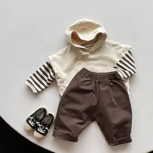 Tenue enfant avec sweat à capuche beige à manches rayées et pantalon marron sur table