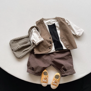 Tenue vintage pour enfants avec gilet à pois, short marron et baskets sur fond beige