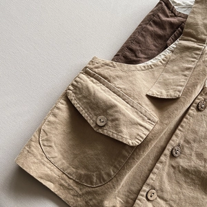 Detailed close-up of khaki cotton vest showing stitching and round wooden buttons