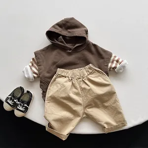 Flat lay of brown hooded vest set for kids with khaki pants and striped sleeve details