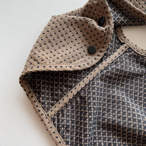 Detail der wendbaren Kleinkindweste mit braunem Karostoff und mattem schwarzem Knopf
