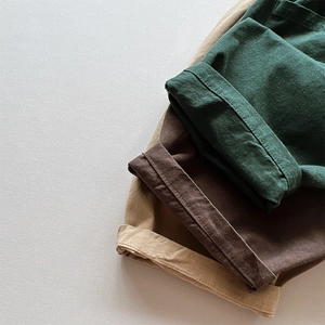 Pantalon large pour enfants plié en olive, marron et kaki avec ourlet retroussé et texture