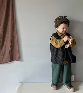 Détail d'une tenue enfant avec chemise, gilet à pois et pantalon large vert foncé