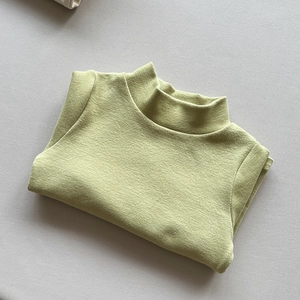 Detailed close-up of the soft olive green ribbed texture and turtleneck of this kids top