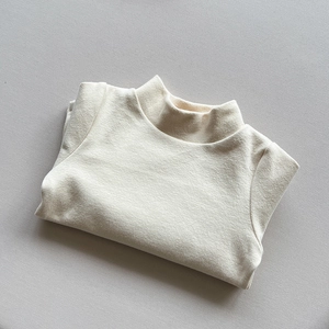 Flat lay detail of a beige thermal turtleneck sweater for kids showing soft knit texture