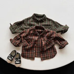 Flat lay of retro plaid flannel shirts for kids in green and brown with canvas shoes