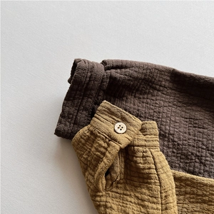 Detail of soft double-layer cotton fabric cuffs with natural wood buttons in mustard and brown