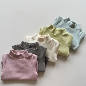 Folded kids mock neck base layers in pink, gray, cream, mustard, and green cotton fabric