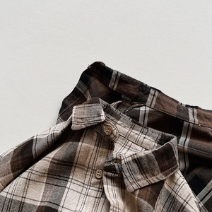 Detailed view of the vintage plaid shirt collar with wooden texture button and brushed fabric