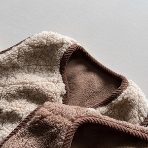 Dettaglio ravvicinato del colletto del gilet in sherpa con bordo in velluto marrone