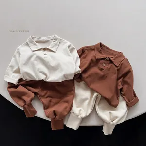 Flat lay of soft cotton baby polo shirts and sweatpants sets in cream and brown tones