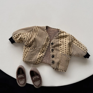 Detail of baby quilted cotton jacket with polka dot print and matching lamb wool soft shoes