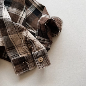 Close-up of flannel plaid shirt cuff with vintage round button and fine stitching
