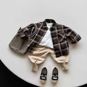 Flat lay of kids' autumn outfit with plaid shirt, white t-shirt, and beige joggers