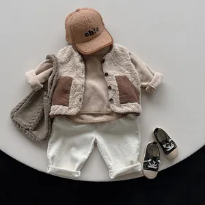 Flat lay of warm beige fleece vest and cotton pants set for kids with chic brown cap