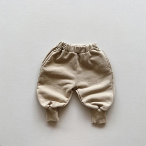 Detail of light beige cotton joggers for kids with elastic waistband and ribbed cuffs