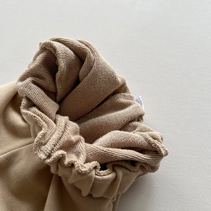 Macro detail of khaki cotton sweatpants showing elastic cuff and internal French terry fabric