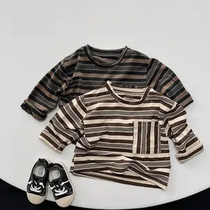 Gros plan de t-shirts rayés à manches longues pour enfants et baskets en toile noire à plat
