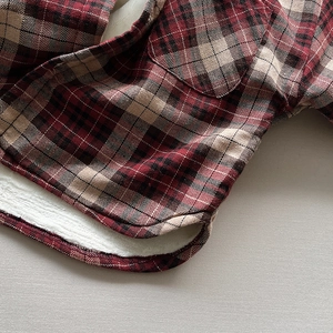 Detail view of red plaid shirt for kids with warm white fleece lining and curved hemline