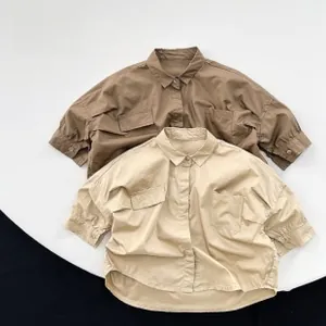 Vue détaillée de chemises pour enfants en coton marron et beige avec grandes poches