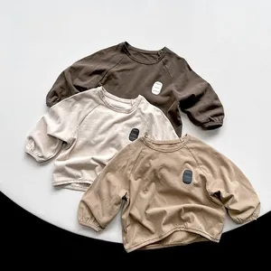 Detailed close-up of soft cotton kids long sleeve tees in coffee, beige, and khaki tones