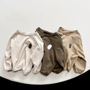Flat lay detail of kids long sleeve cotton T-shirts in cream, brown and khaki colors