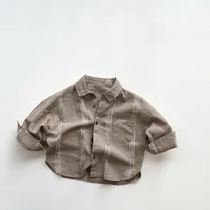 Détail d'une chemise en coton pour enfant avec rayures brunes et poche de poitrine classique