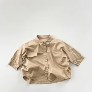 Vue à plat d'une chemise en coton kaki ample avec double poche poitrine et ourlet arrondi