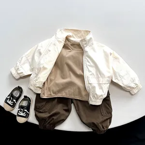 Flat lay of cream utility jacket, brown tee, and cargo pants for children's outdoor wear