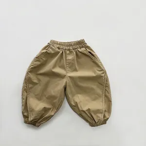 Detail view of khaki cotton jogger pants showing elastic waist and ribbed ankle cuffs