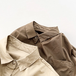 Détail de chemises en coton montrant des coutures soignées, des boutons et une texture fine