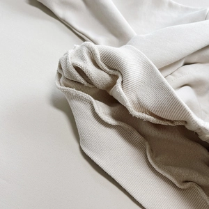 Detail der hochwertigen French-Terry-Baumwolle und Rippbündchen am hellen Hoodie