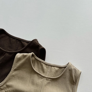 Close-up of brown and khaki knit vests showing fine double-stitch seams and cotton texture