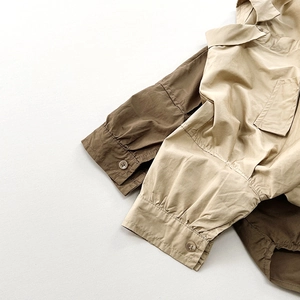 Détail d'une chemise enfant oversize avec poignets boutonnés et poche poitrine