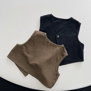 Detail view of knit kids vests in black and brown colors with a single button V-neck design