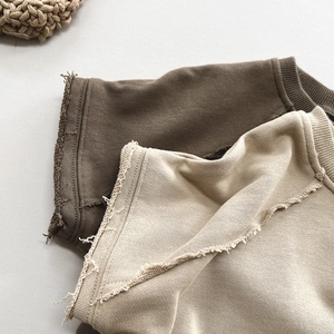 Macro view of minimalist knit cotton vests showing raw edge detail and textured fabric