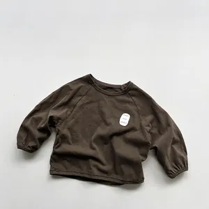 Detail view of cotton brown kids sweatshirt with raglan sleeves and white chest graphic